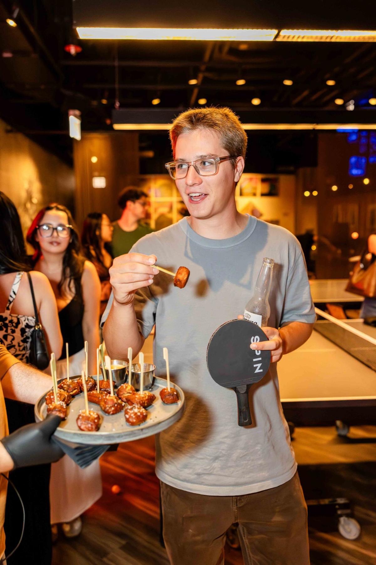 A guest at a SPIN event with a SPIN paddle and party bites